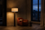 Sculptural floor lamp casting a warm pool of light onto a single lounge chair and open book in a moody tadelakt reading nook